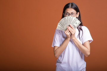 Woman holding cash notes isolated in orange background.