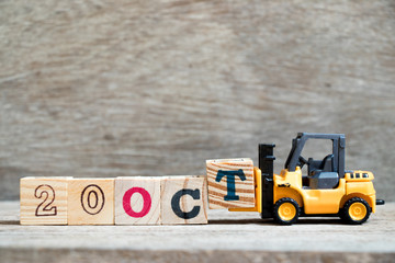 Toy forklift hold block T to complete word 20 oct on wood background (Concept for calendar date in...