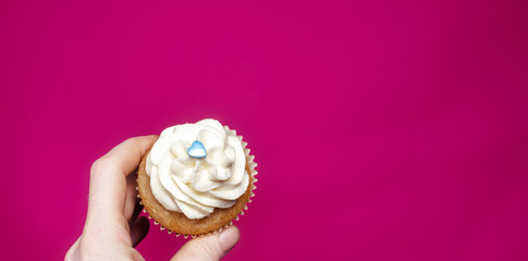Cupcake with hand on pink background