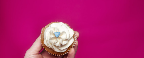 Cupcake with hand on pink background