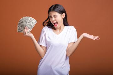 Woman holding cash notes isolated in orange background.