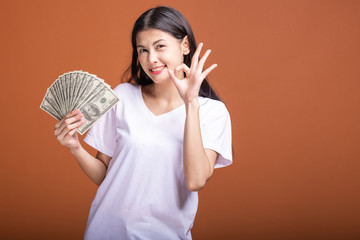 Woman holding cash notes isolated in orange background.