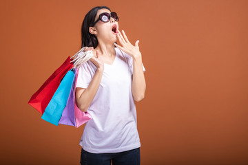 Woman holding shopping bag isolated in orange background.
