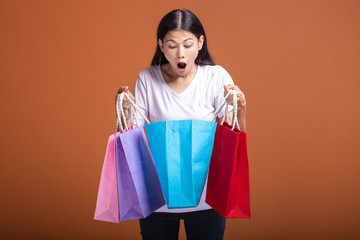 Woman holding shopping bag isolated in orange background.