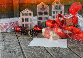 a New year and Christmas  card / miniature wooden houses, gifts,spruce branches ,cones on the old wooden table