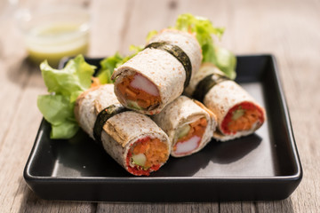 Salad roll with whole wheat bread wrapped on black dish