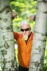 Young man with a blonde hair and beard leaning on a tree in nature