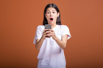 Woman using mobile phone isolated over orange background.