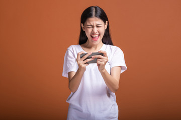 Woman playing mobile game isolated over orange background.