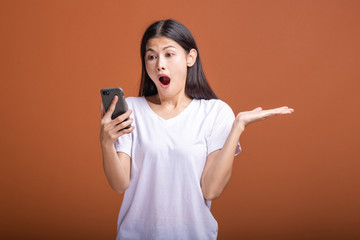 Fototapeta premium Woman using mobile phone isolated over orange background.