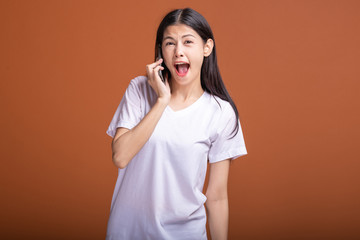 Woman using mobile phone isolated over orange background.