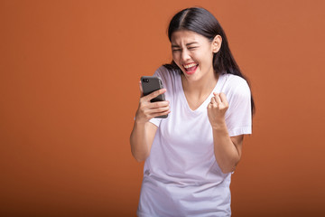 Fototapeta premium Woman using mobile phone isolated over orange background.