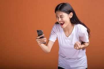 Woman using mobile phone isolated over orange background.