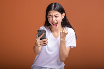 Woman using mobile phone isolated over orange background.