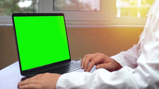 Doctor Using Laptop Touchpad, notebook with a green screen chroma key