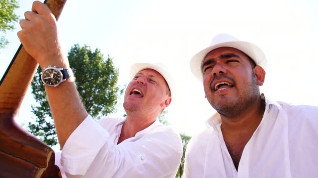 Musicians with double bass and guira give street concert in the city at sunset. Live camera. Slow motion