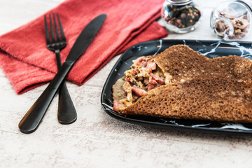 Black wheat and wheat galette topped with cooked ham and emmental cheese