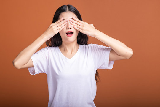 Woman Cover Her Eyes Isolated In Orange Background.