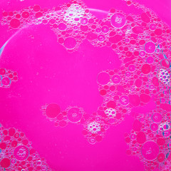 Circles of oil in water on a pink purple background. Abstract background for text.