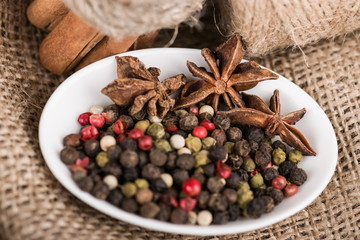 In a bowl, there is colorful pepper. Rough fabric with cinnamon