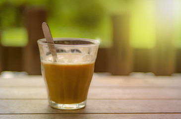 Hot Latte coffee is placed on the old wooden table in a warm morning on the balcony overlooking the fresh garden.