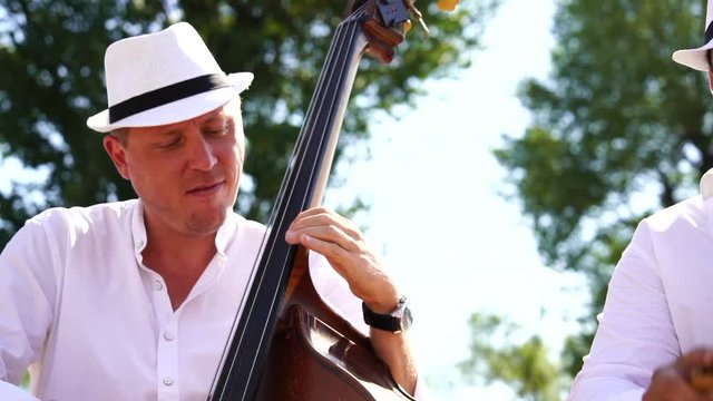Musicians with double bass and guira give street concert in the city at sunset. Live camera. Slow motion