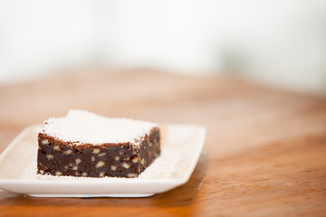a brownie on a square plate with powdered sugar on top