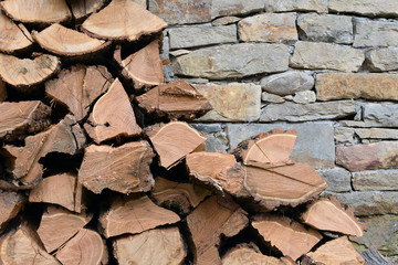 Pile of firewood logs by stone wall - detail