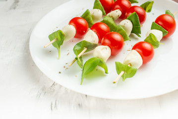Salad Caprese - shish kebab with tomato, mozzarella and basil, Italian cuisine and a healthy vegetarian diet on a light background. with copy space, top view, flat lay