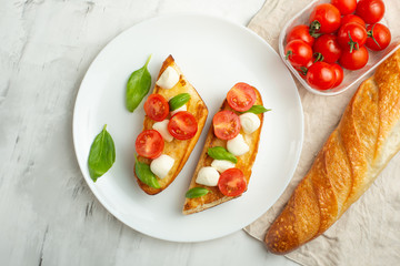 Bruschetta with tomatoes, mozzarella cheese and basil in a white plate. Traditional Italian snack or snack, antipasto. With space for writing.
