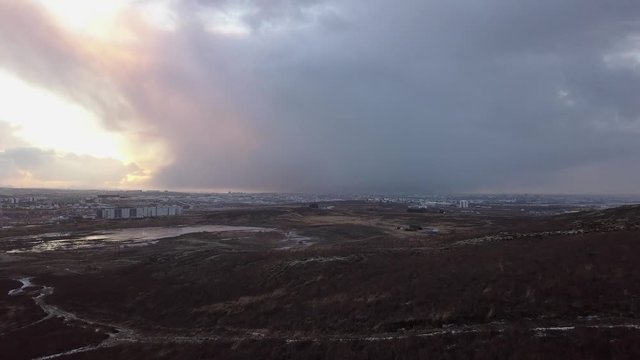 Stormy drone view towards distant Reykjavik with giant raincloud