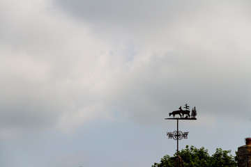 Cloudy sky with weather vane, background.