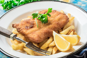 A piece of fried cod with fries on a plate.