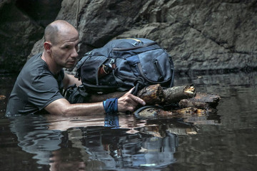 Man is crossing a river pushing a raft