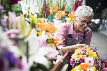 Senior woman arranges flowers on local flower market