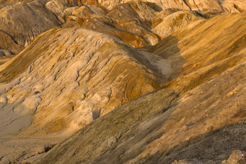 orange clay hills in the desert, lit by the setting sun