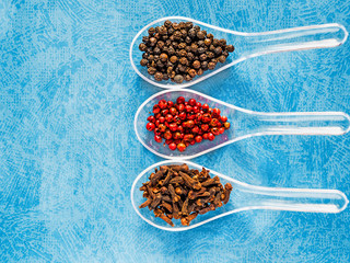 Assortment of dry spices on spoons isolated on a textured blue background. Three spoons with spicy ingredients on textured background, space for text, multiple colors