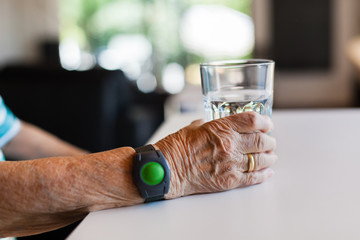 Hand of senior lady holding a glass of water on table