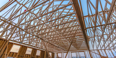 Looking up at new wood beams of building wide pano