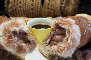 Cup of hot coffee on day of winter cold. Warm scarf and mittens