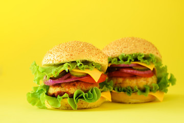 Fast food - juicy hamburger, french fries potatoes and cola drink on yellow background. Take away meal. Unhealthy diet concept with copy space