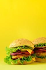 Fast food frame. Delicious meat burgers on yellow background. Take away meal. Unhealthy diet concept with copy space