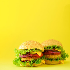 Fast food concept. Square crop. Juicy homemade hamburgers on yellow background. Take away meal. Unhealthy diet frame with copy space