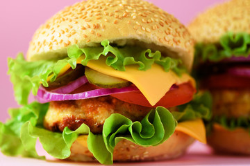 Macro view of tasty burger with beef, cheese, lettuce, onion, tomatoes on yellow background. Close up banner. Unhealthy diet concept and copy space