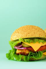 Macro view of tasty burger with beef, cheese, lettuce, onion, tomatoes on blue background. Close up banner. Unhealthy diet concept. Copy space