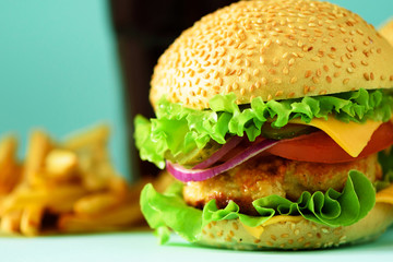 Homemade cheese burger or hamburger served with french fries on blue background. Copy space. Fast food for breakfast, lunch.