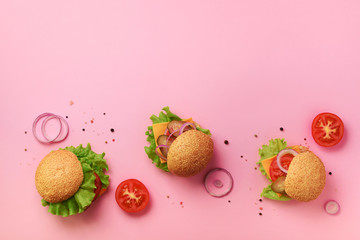 Tasty burgers with beef, tomato, cheese, onion, cucumber and lettuce on pink background. Top view,...