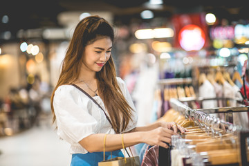 Fototapeta na wymiar Beautiful Attractive Asian young woman choose cloth hang on shelf in Clothes store feeling so happiness and enjoy in shopping mall,Selective focus,Fashion and Shopping concept