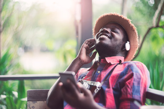 African Man Listening To Music. Guy Wearing Headphones With Closed Eyes On Green Natural Background