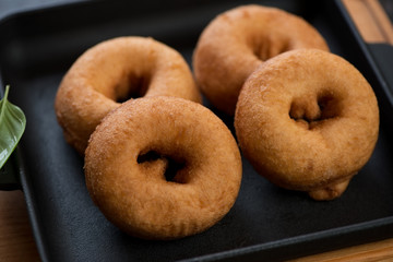Close-up of four freshly cooked donuts in a cast-iron pan, selective focus